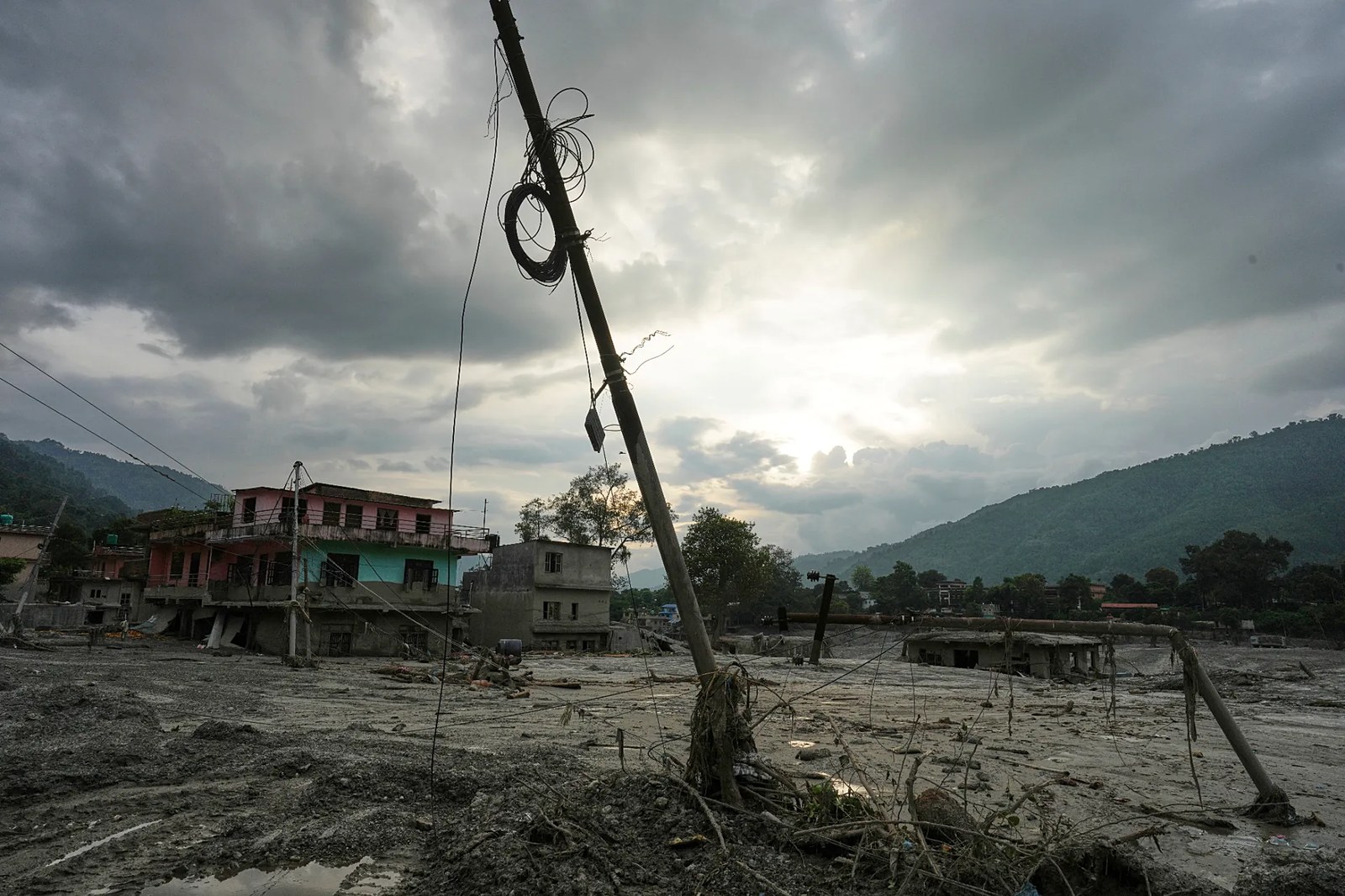 Nepal'in Nuwakot bölgesindeki Devighat çevresinde ani selin ardından hasar gören bir elektrik direği yan yatmış halde, 28 Ağustos 2026