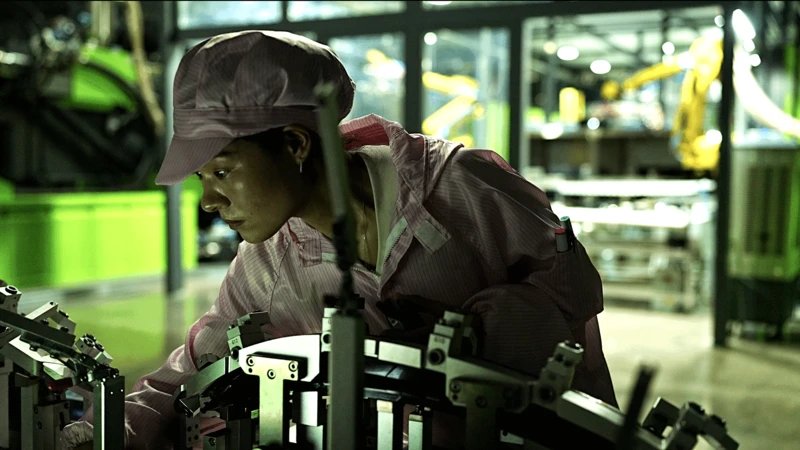 Leapfrog Motors fabrikasında çalışan genç bir kadın işçi, bir makineyi inceliyor.