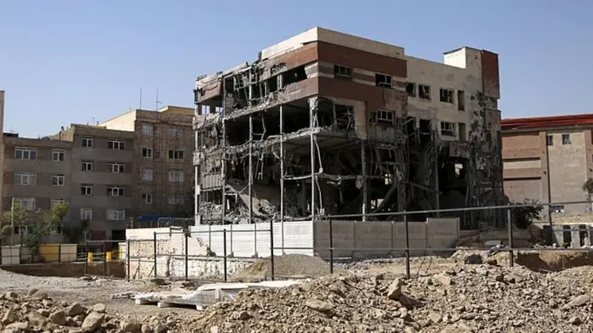 Tahran'da beş katlı bir binanın genel görünümü. Bina, bildirilen bir füze saldırısı sonucu bombalanmış, dış tuğla duvarları artık görünmüyor ve bunun yerine bina içi boşalmış durumda ancak hala ayakta duruyor. Etrafı molozlarla çevrili.