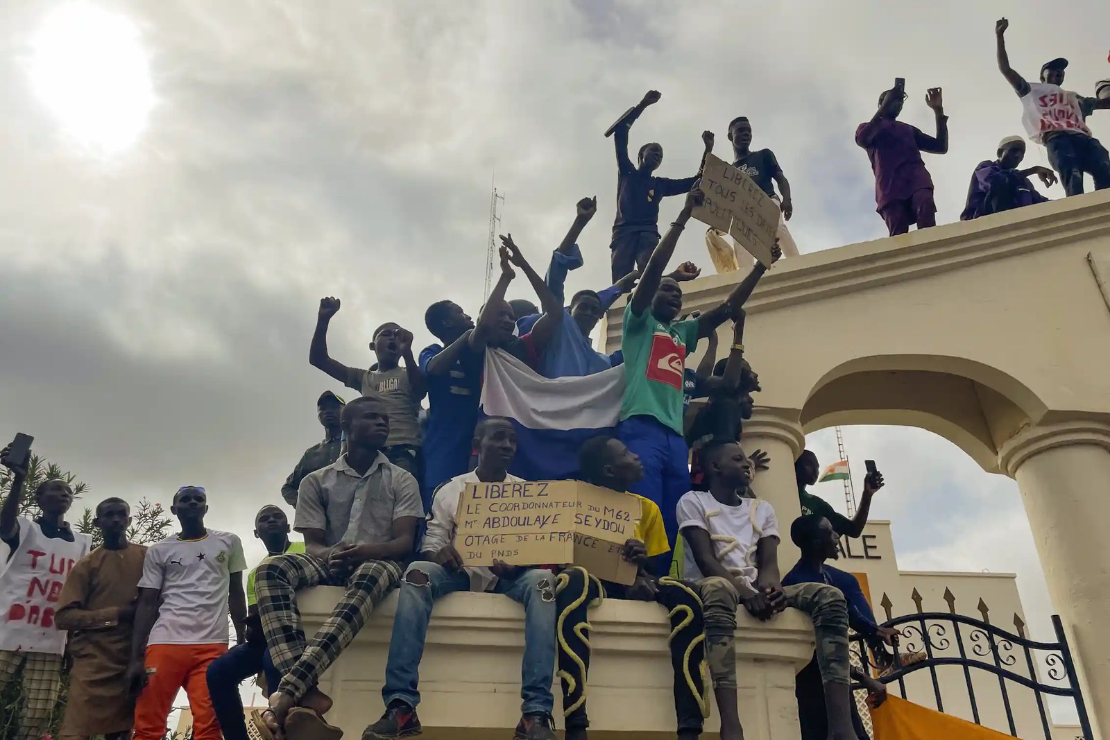 People standing on a building raise their fists in triumph.