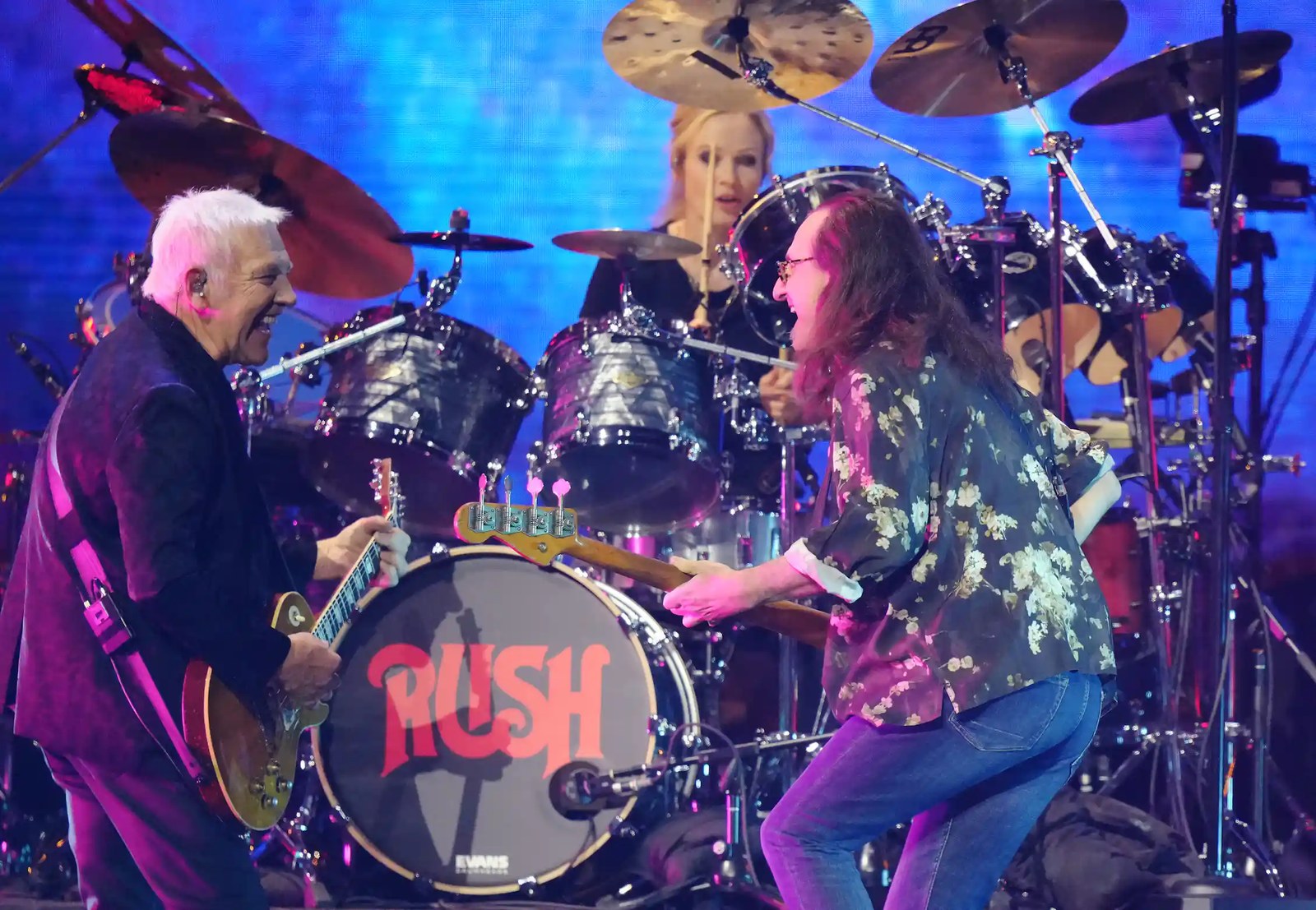 Two musicians perform on stage, smiling at each other.
