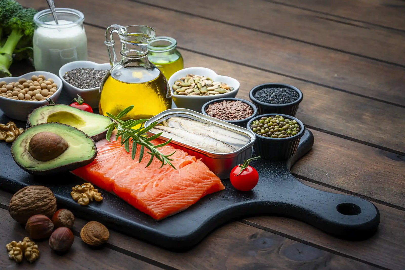 A wooden slab containing healthy foods such as salmon and avocados.