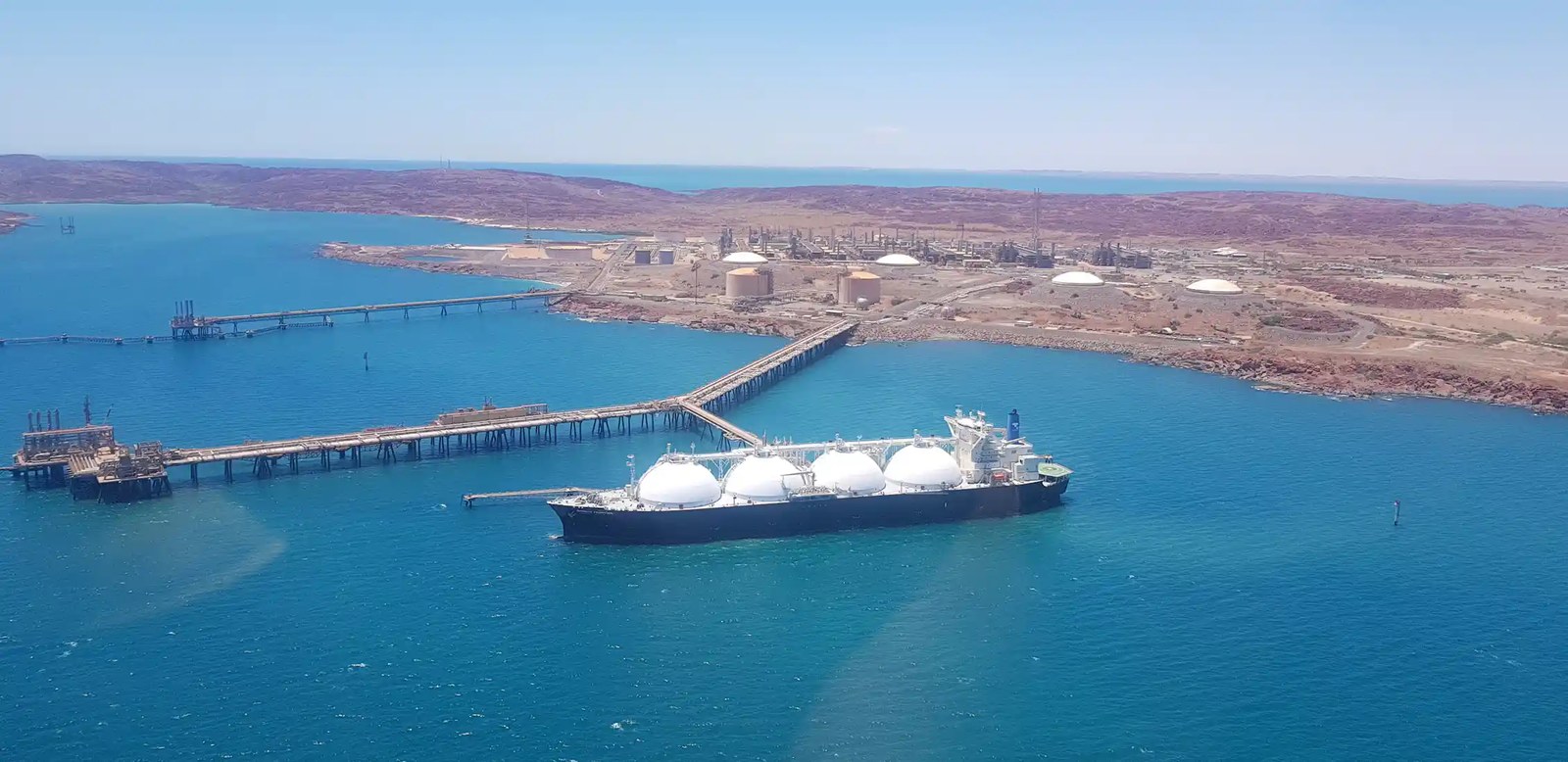 LNG tanker being filled, arid land behind.