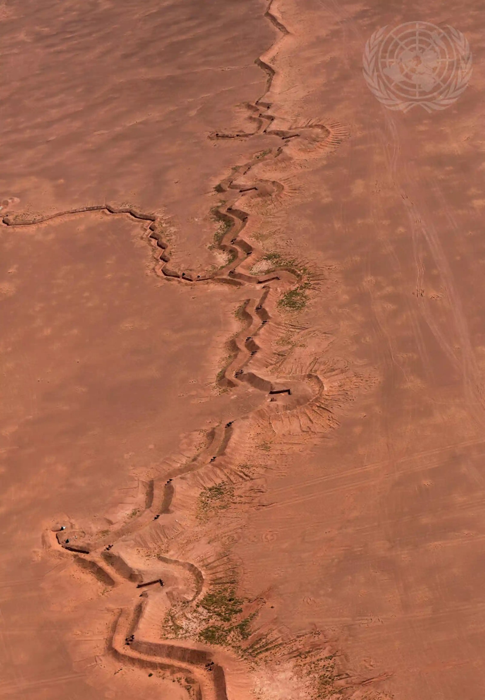 A shot of a desert with a trench running from one end of it to another