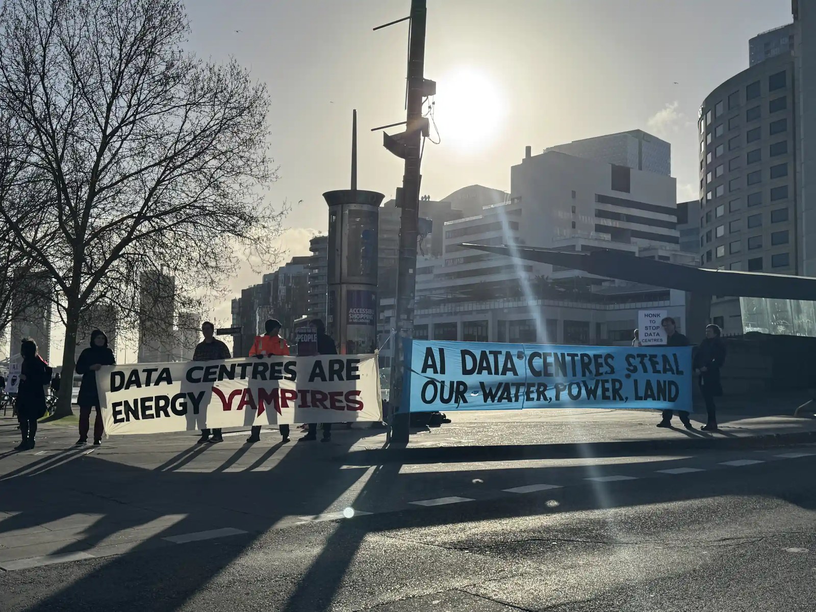 people protesting data centres, banners talking about environmental impact. cold day in city.