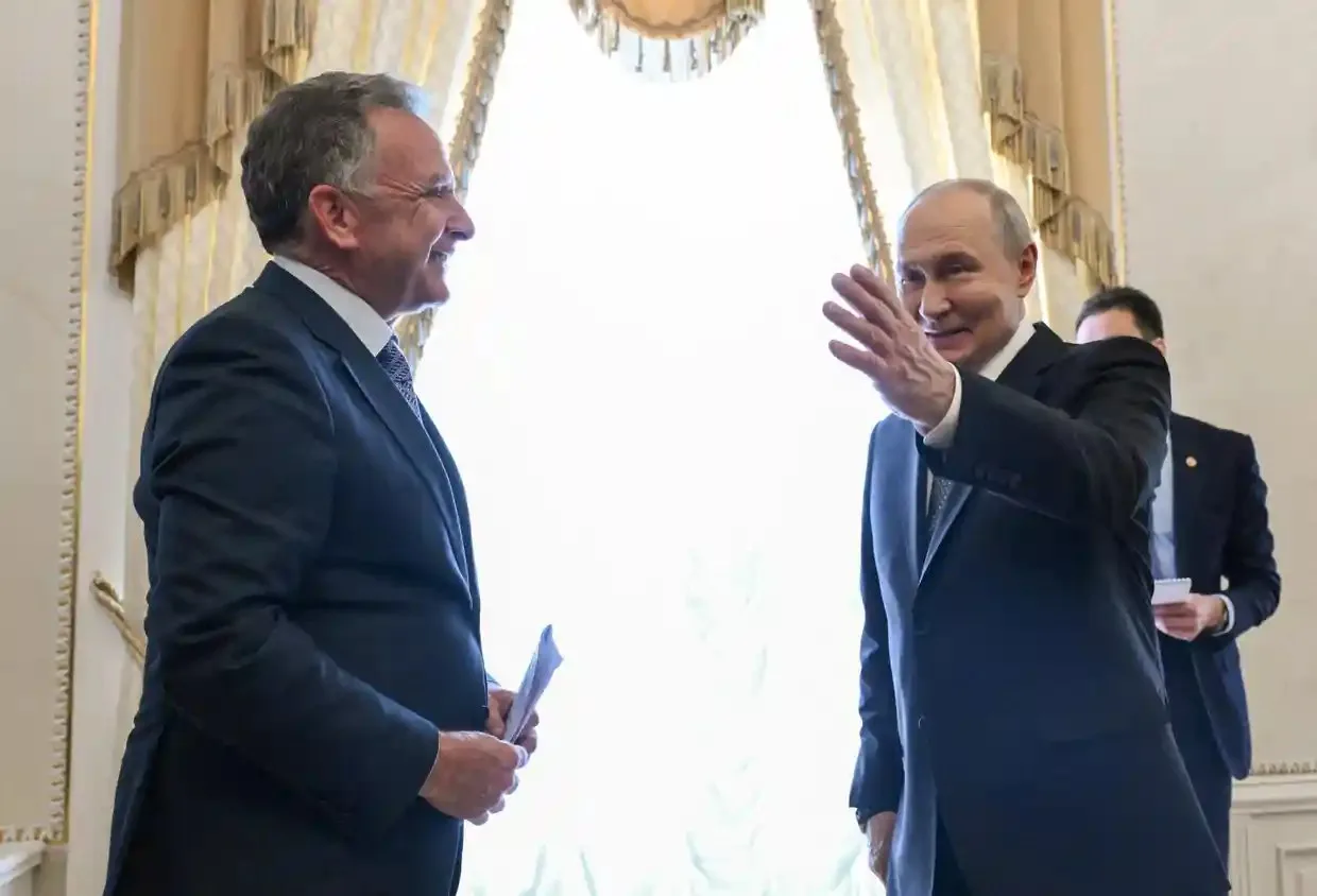 Putin waves and smiles while walking past Steve Witkoff in a grand palace room