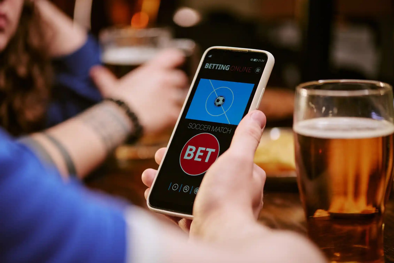 Man holds phone and places a bet on football.