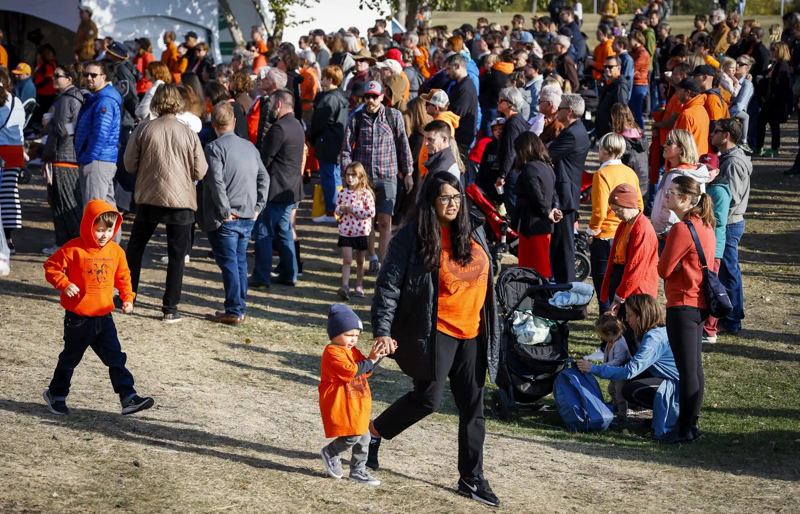 People seen walking in orange T-shirts outdoors.