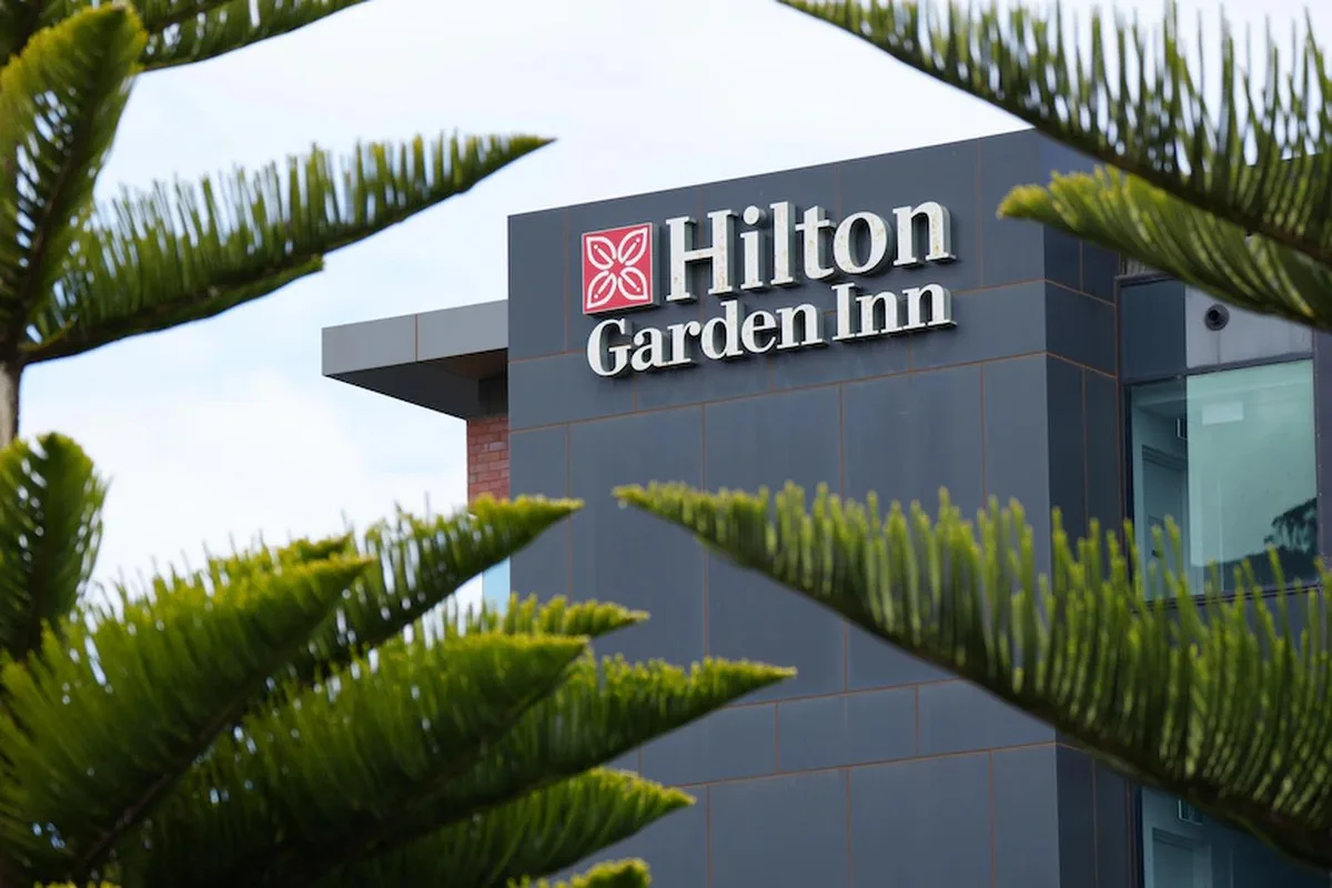 Hilton Garden Inn sign on black wall through trees