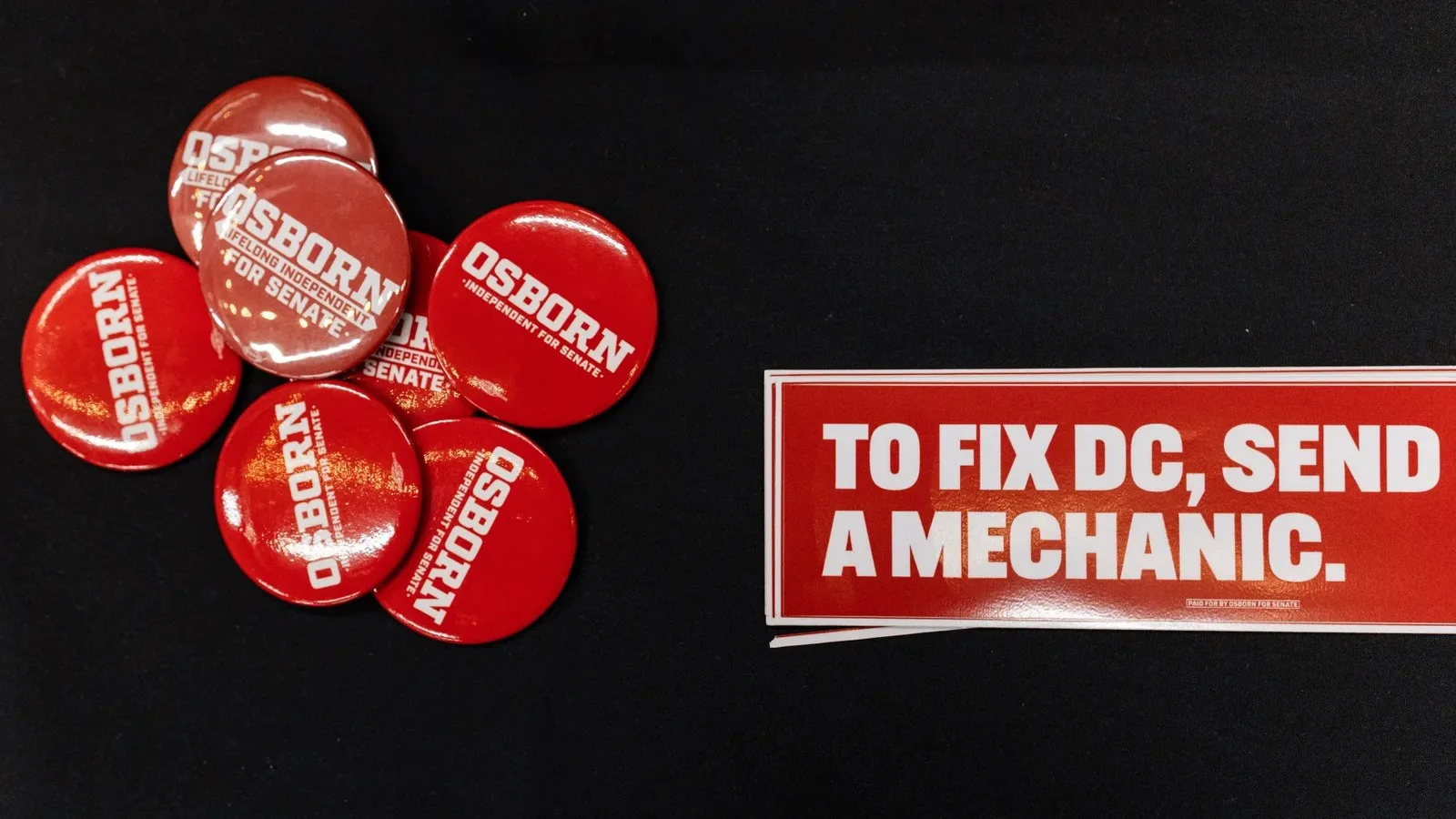 Pins and bumper stickers supporting Dan Osborn's candidacy for U.S. Senate sit on a campaign table on Sept. 3 at Pals Brewing Company in North Platte, Neb. Osborn, a 51-year-old Navy veteran, is running as an independent.