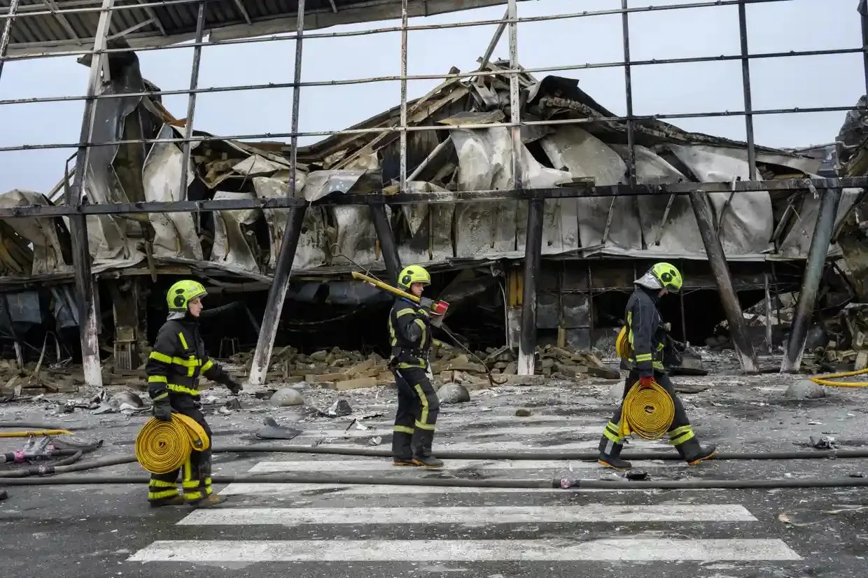 Emergency workers walk by a damaged shopping centre in Kyiv, Ukraine.