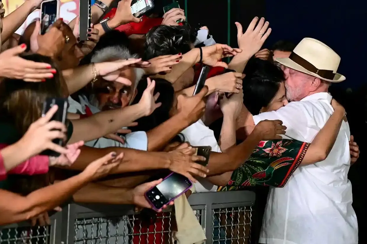 Lula hugs a woman who is part of a crowd of supporters.