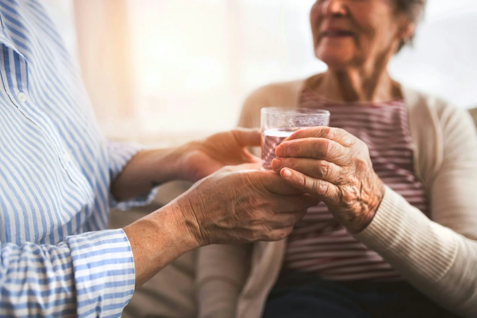 Caregivers can offer water and other drinks to older adults throughout the day, rather than waiting for them to ask. (Unsplash+/Getty Images)