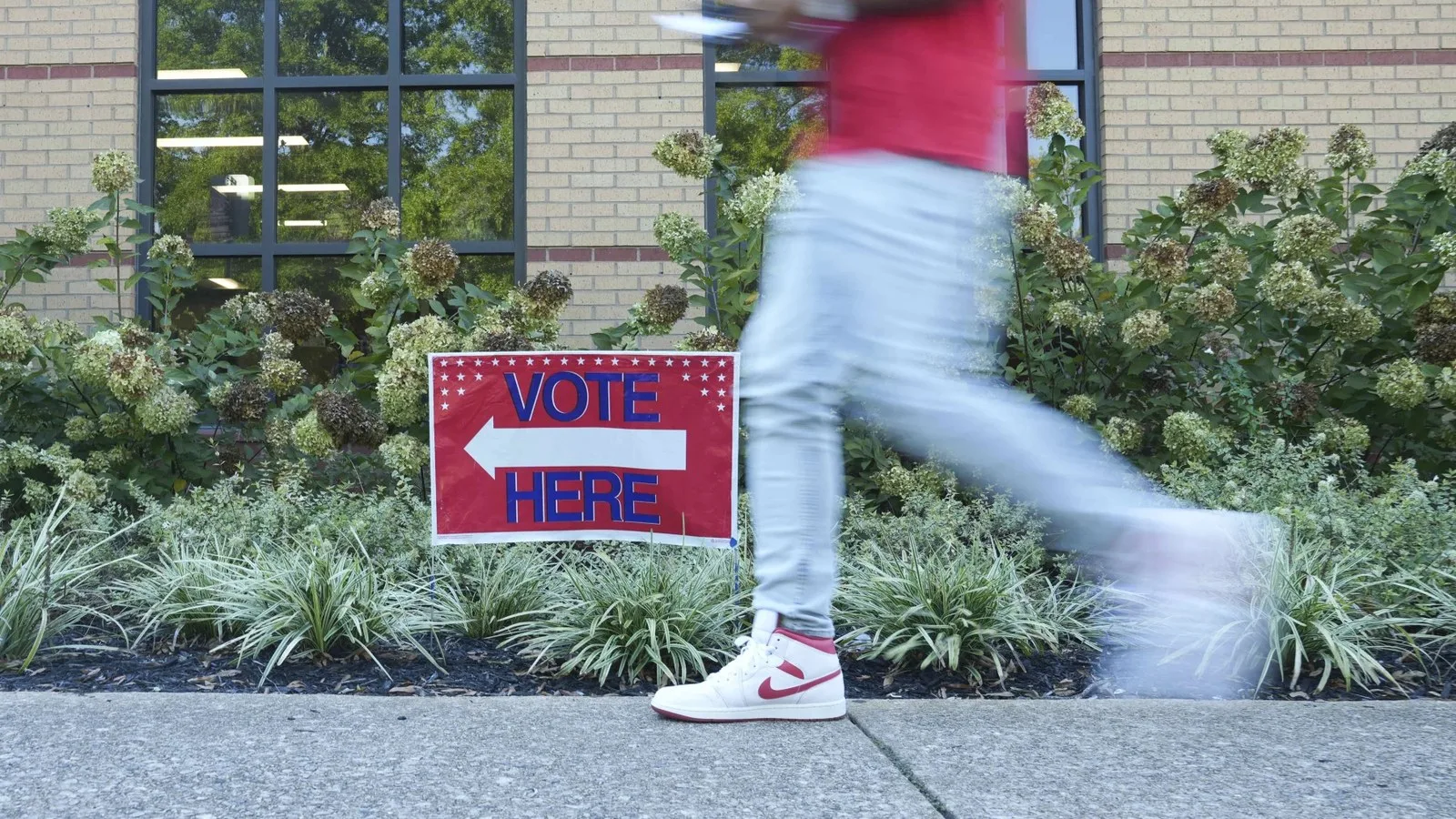 A person walks past a voting sign at the East Point Library on Tuesday, the first day of early voting, in Atlanta.