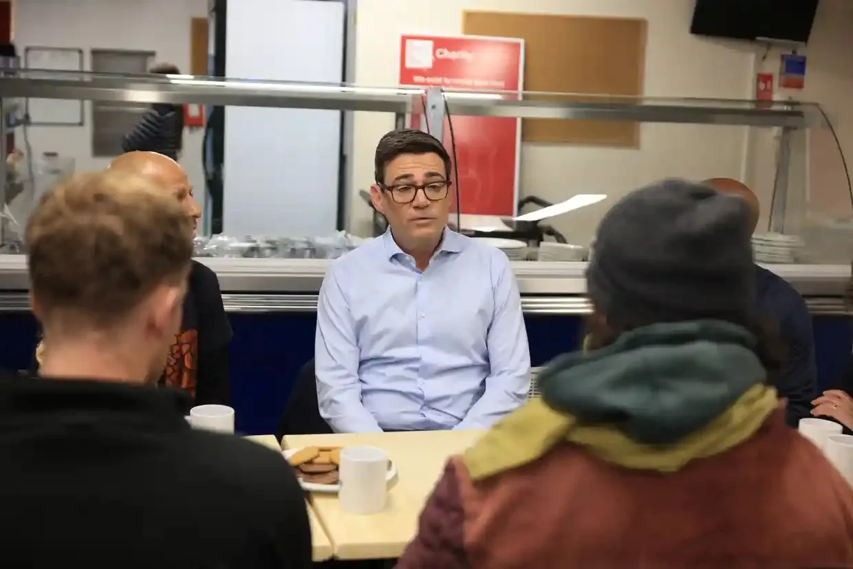 Burnham speaks while seated at a table during a charity visit