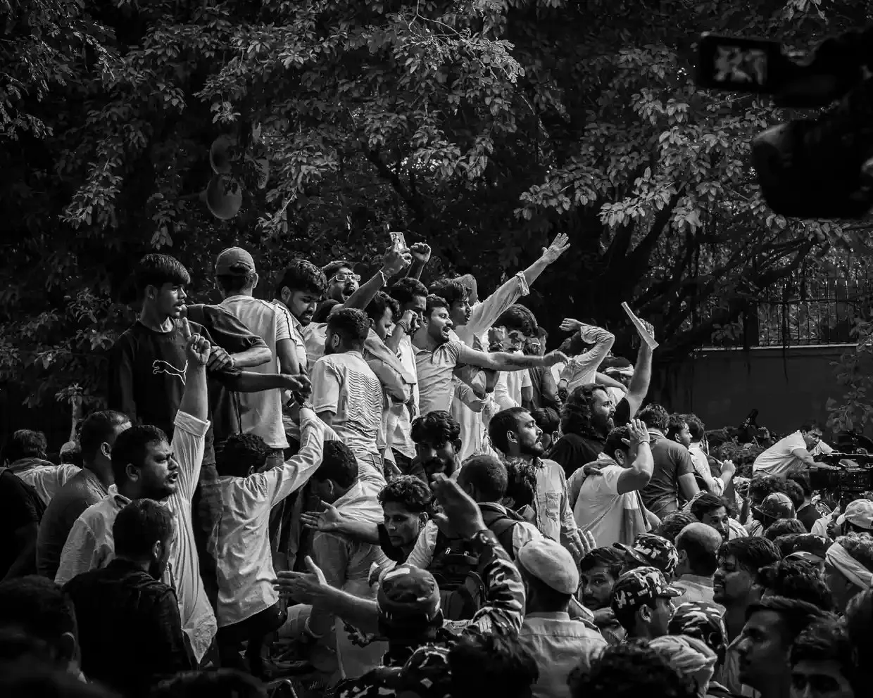 A crowd of student protesters in India raise their fists and shout 