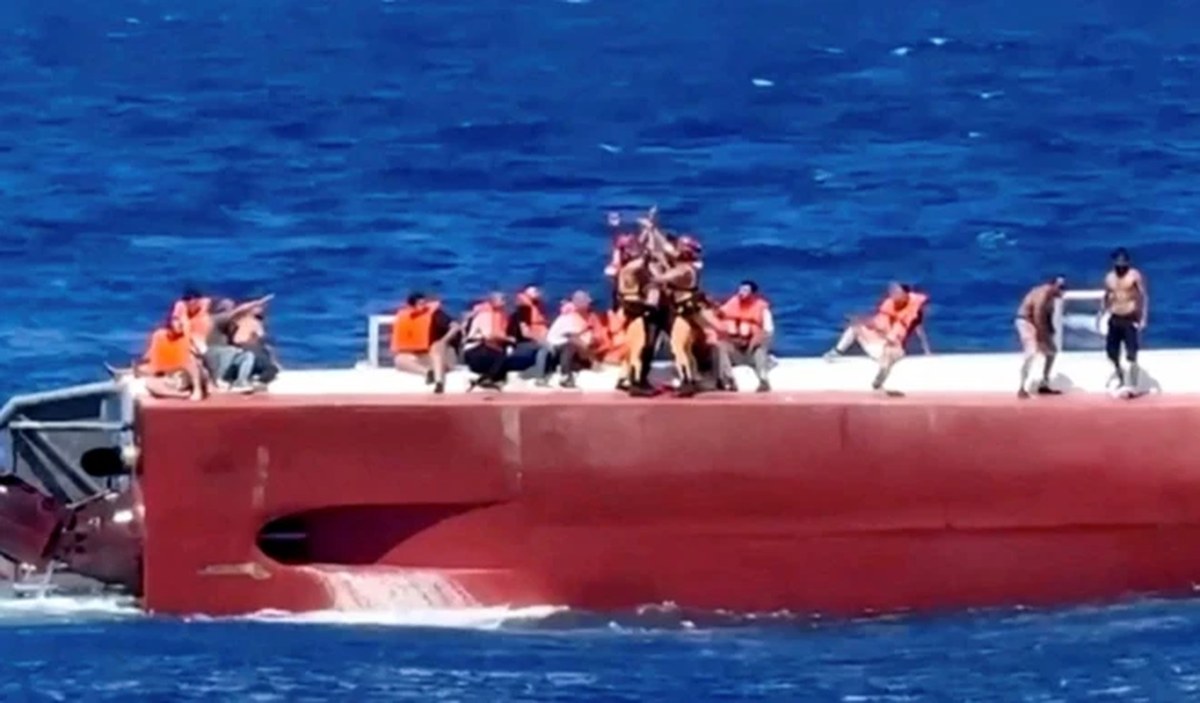 Bir helikopterden sarkıtılan iple ters dönen katamarandan yolcular kurtarıldı. Kırmızı renkli bir deniz aracının üzerinden yaklaşık15 kişi görünüyorr. Çoğu oturuyor ve can yeleği giymişler