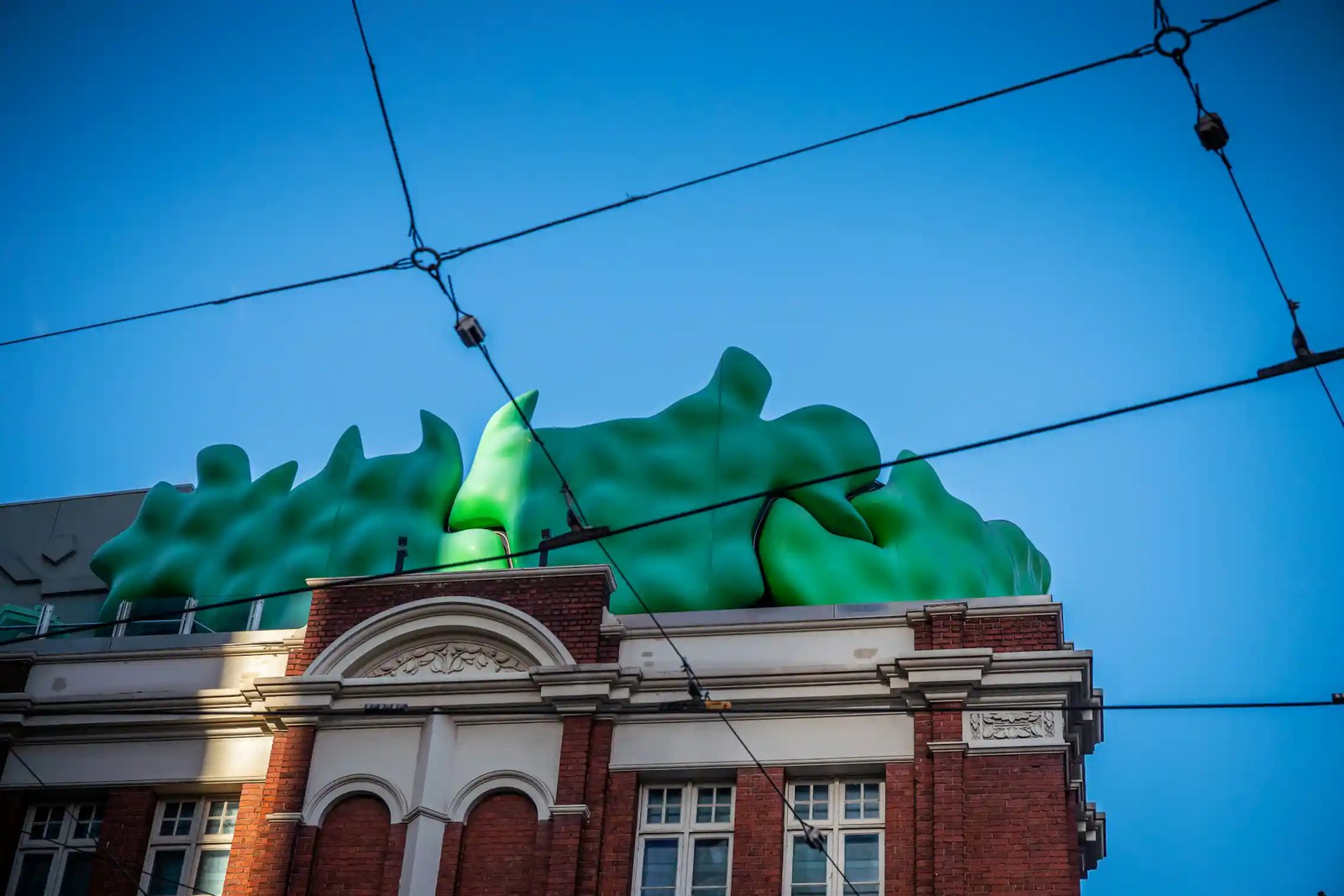An old red brick building with a green sculpture on its roof.