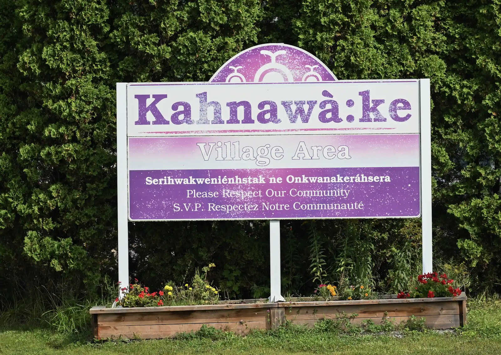 A purple sign says Kahnawà:ke - please respect our community.