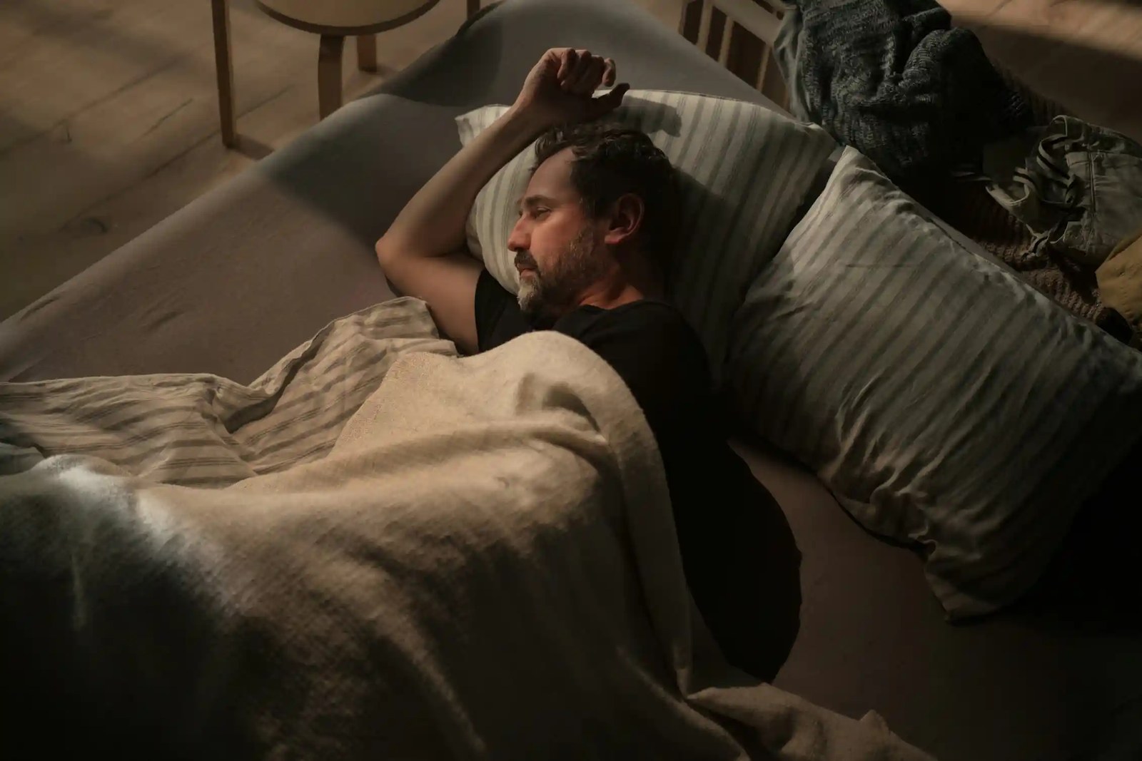 A man lies in bed in a dark room