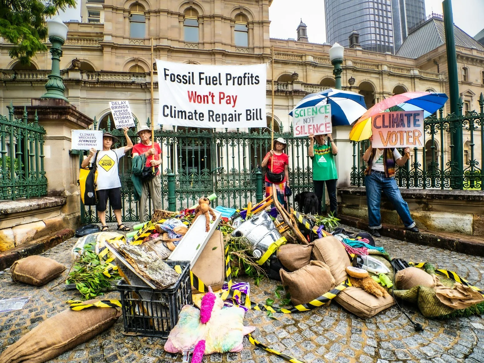 Several people hold signs critiquing the climate costs of fossil fuel projects. Malcolm Paterson